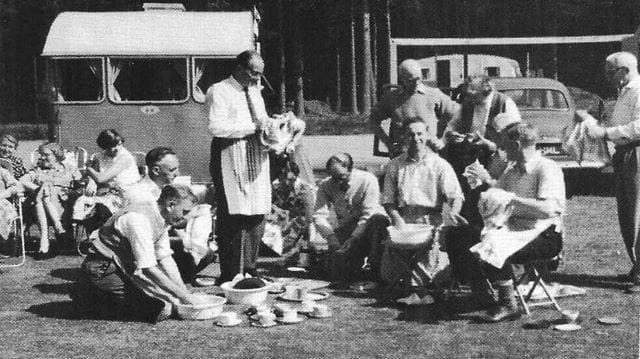 Black and white photo of the 1960s camping and caravanning group having a picnic outside
